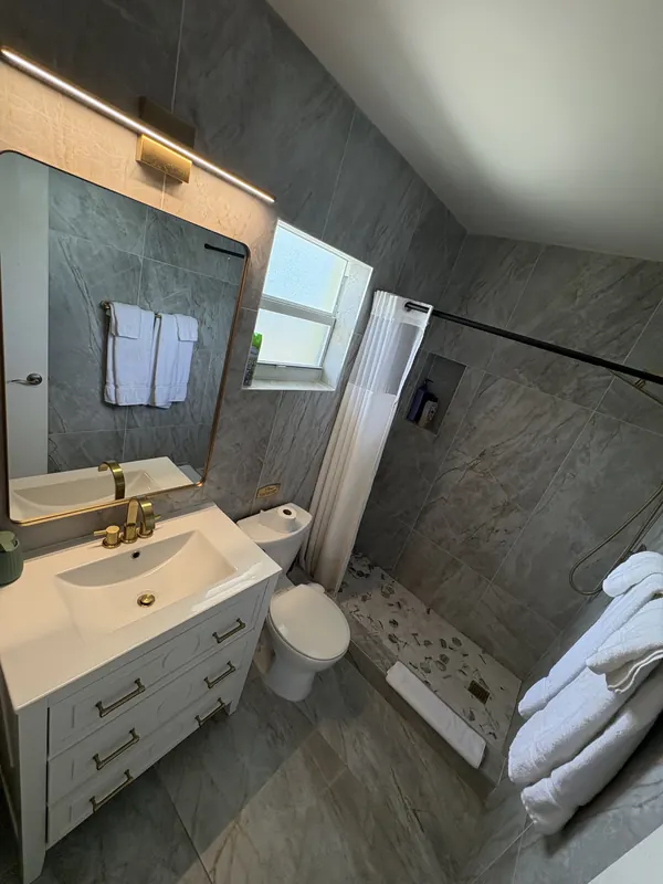 Gray tile bathroom remodel with white vanity