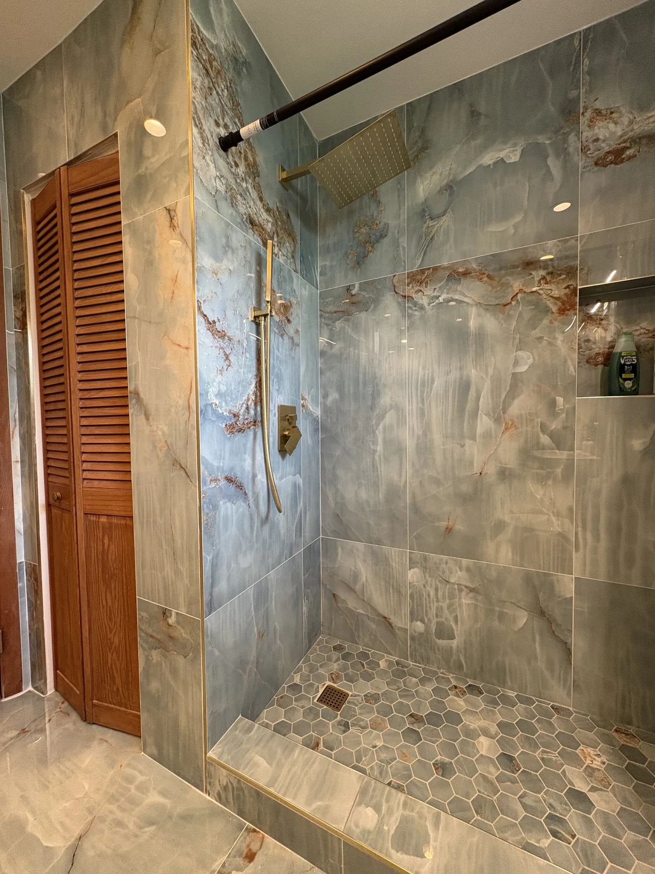 Brass rainfall shower and blue stone-look tile